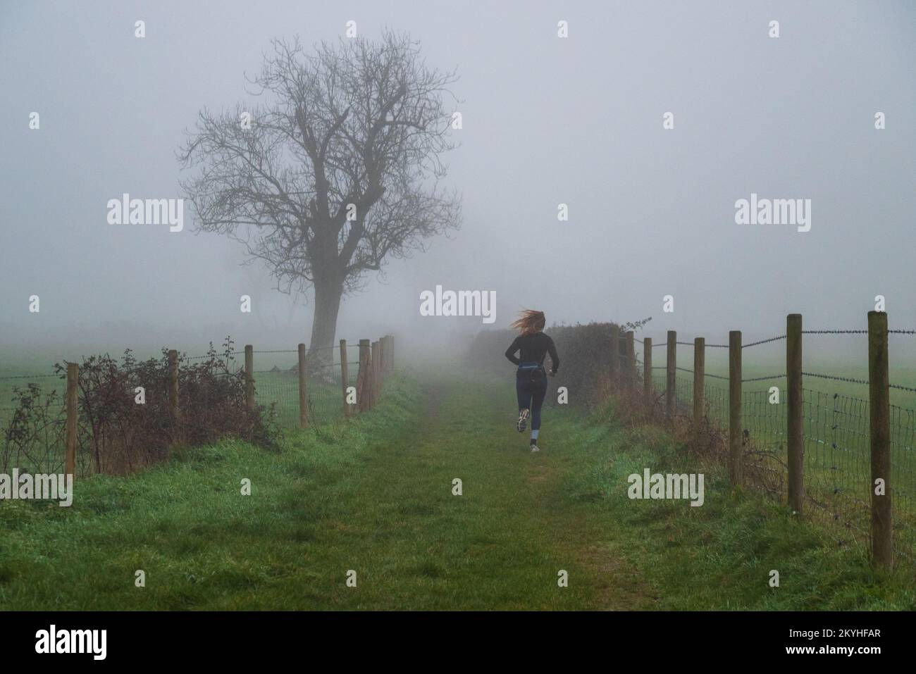 Avon Valley, Fordingbridge, Hampshire, Großbritannien, 1.. Dezember 2022: Ein Läufer trotzt den Elementen an einem nebligen Morgen am ersten Tag des meteorologischen Winters. Das antizyklische Wetter dominiert und die Tage werden kürzer und kälter. Der Nebel entwickelte sich über der Landschaft von Hampshire mit Temperaturen, die knapp über dem Gefrierpunkt schweben. Kredit: Paul Biggins/Alamy Live News Stockfoto