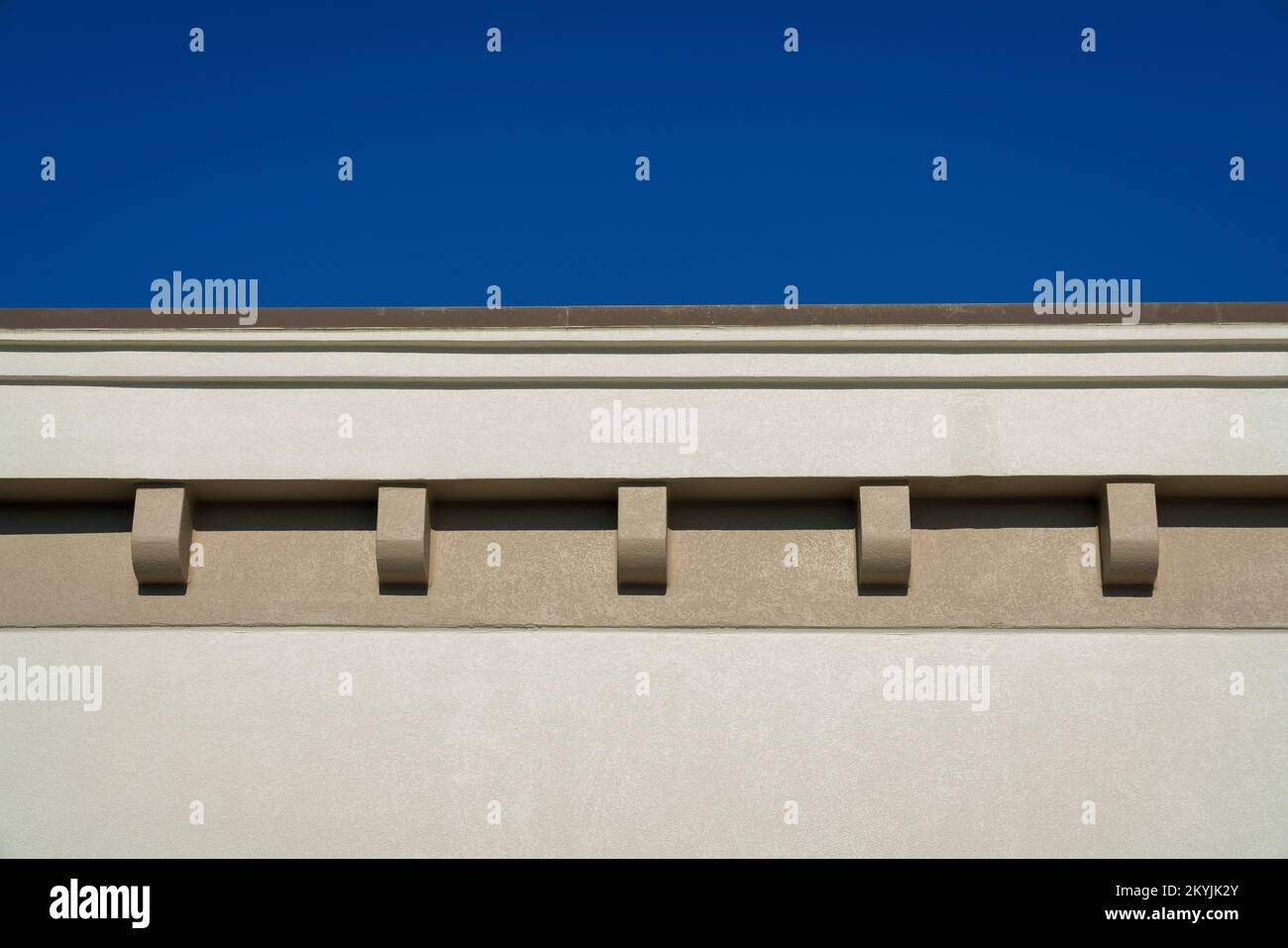 Dächer mit Zahnspuren aus der Nähe in Destin, Florida. Beigefarbenes Gebäude von außen in einem niedrigen Winkel mit Blick auf den klaren blauen Himmel oben. Stockfoto