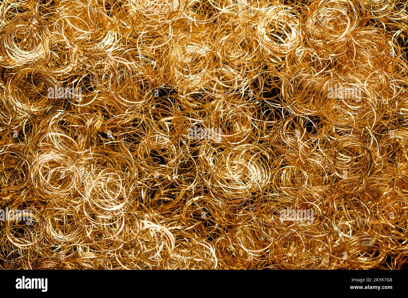 Goldenes metallisches Engelhaar, Hintergrund, von oben. Gelocktes goldenes Lametta-Engelhaar, aus sehr dünnem Kupferdraht. Weihnachtsdekoration. Stockfoto