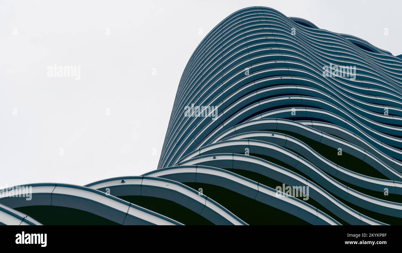 Modernes Gebäude mit wellenförmigem Äußeren. Moderne Architektur der Zukunft. Niedriger Winkel mit Blick auf die Gebäudeetagen Stockfoto