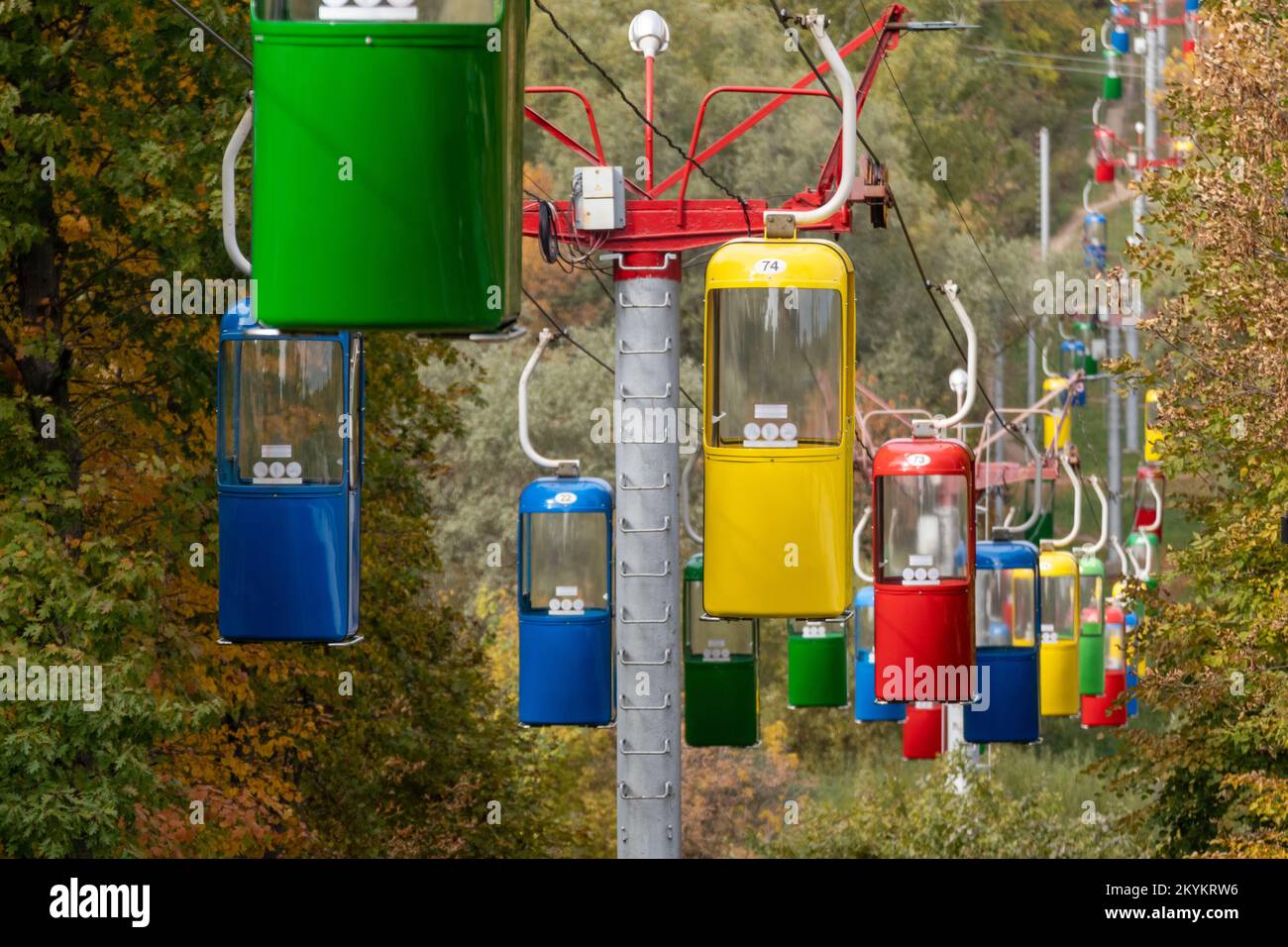Farbenfrohe rot-grün-blau-gelbe Seilbahn-Hütten im Vergnügungspark Kharkiv mit Herbstbäumen Stockfoto