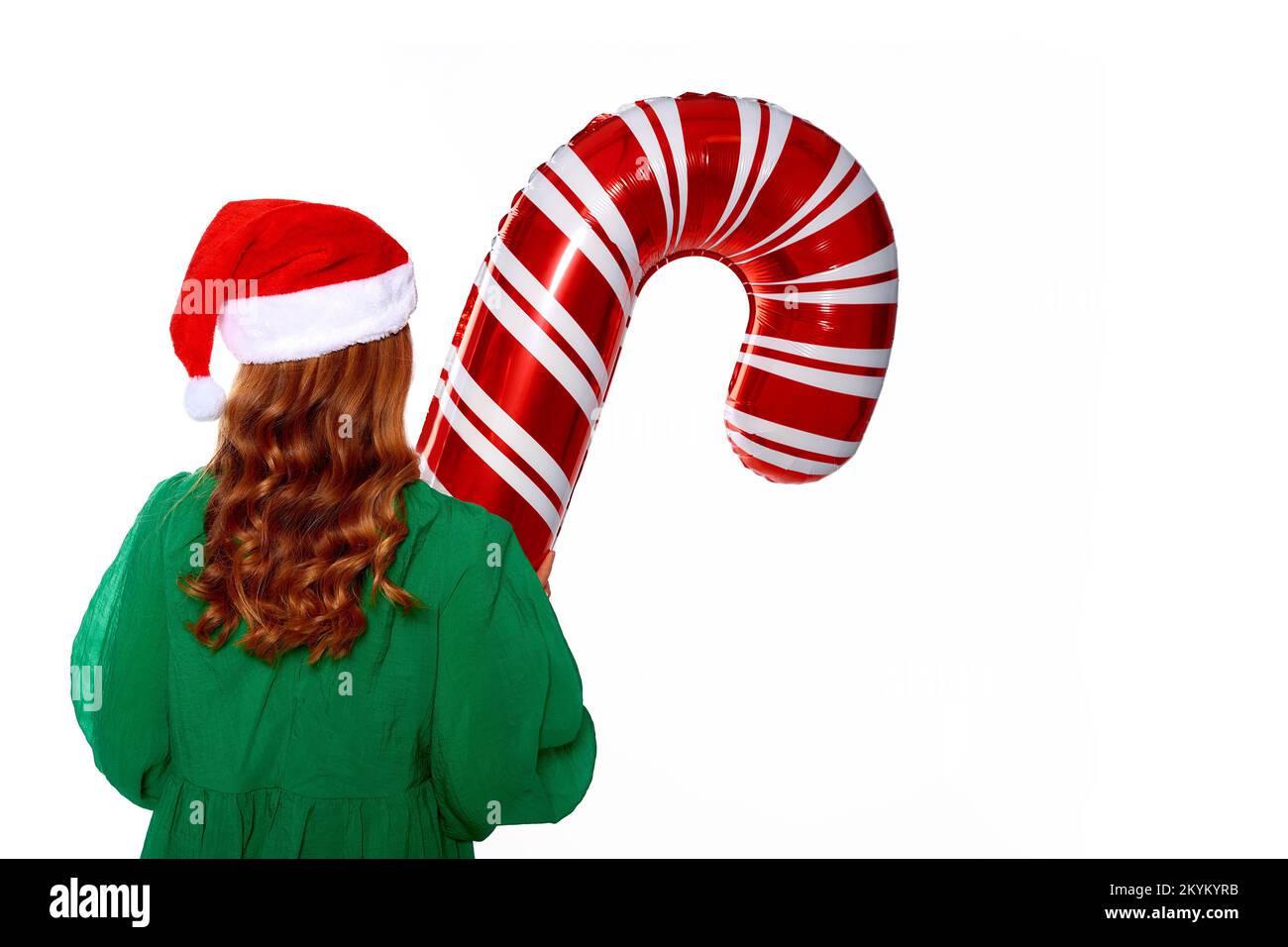 Weihnachtsmädchen hält einen riesigen Zuckerrohr-Ballon in den Händen, trägt ein grünes Kleid, einen weihnachtsmannmütze und rote warme Socken für die Silvesterparty Stockfoto