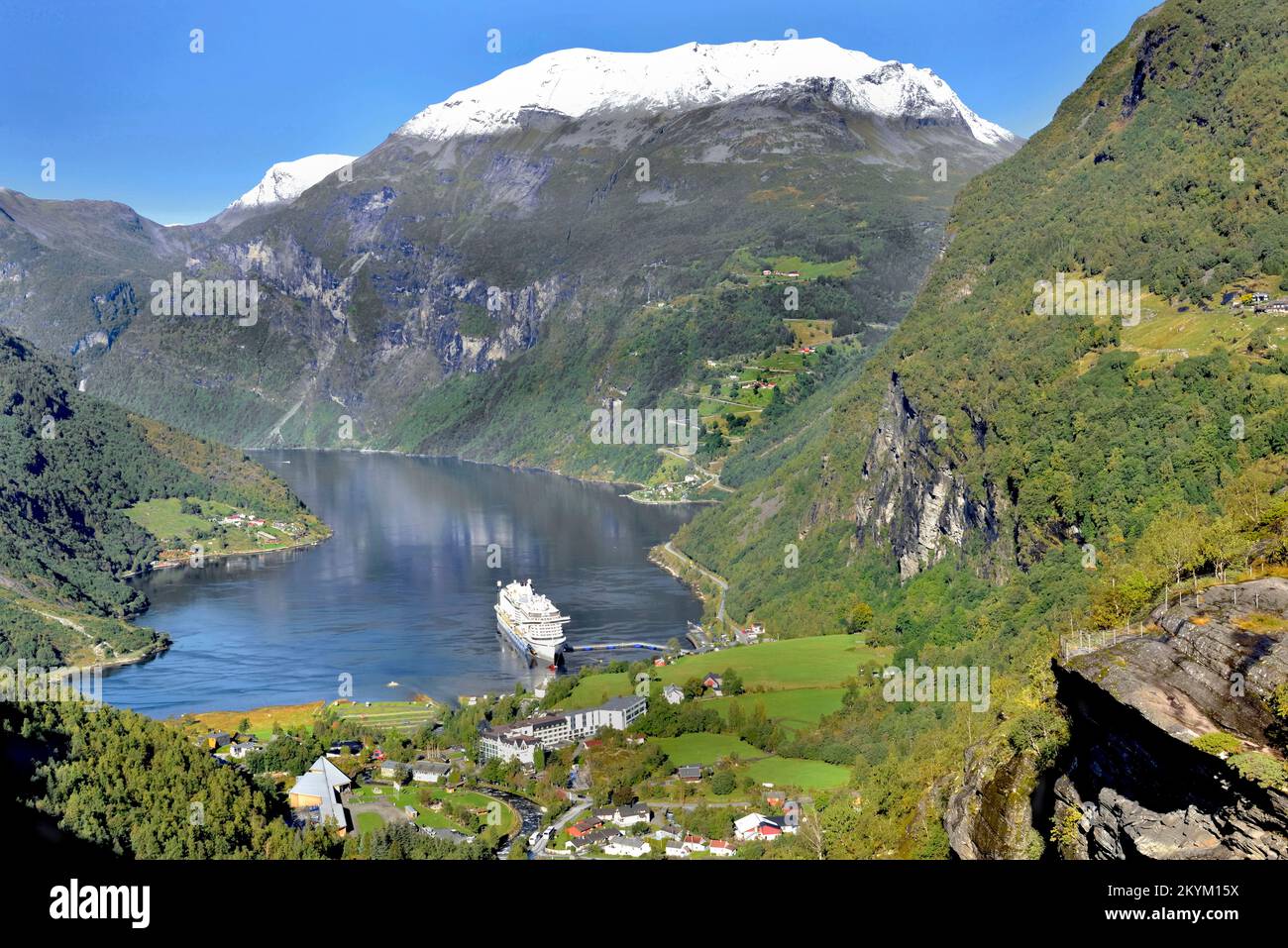 Blick auf den wunderschönen geirangerfjord in Norwegen mit dem Dorf und dem Tourismusboot Stockfoto