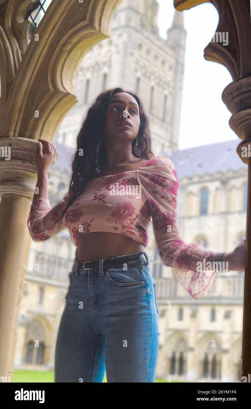 Junge, farbige Frau im Kloster einer Kathedrale in modernen Tüchern. Stockfoto