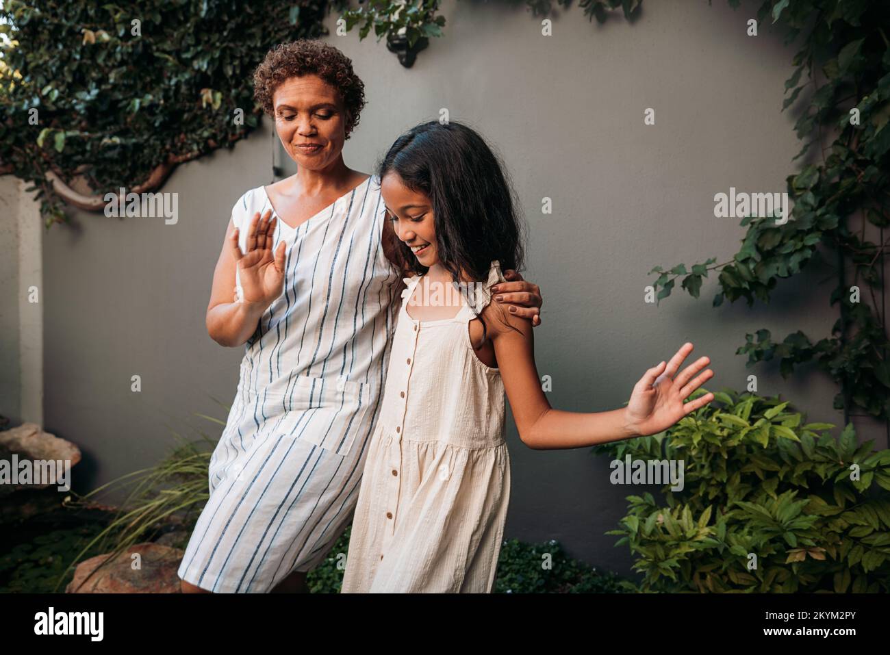 Oma und Mädchen, die Tanz lernen, ziehen zusammen auf dem Hof Stockfoto