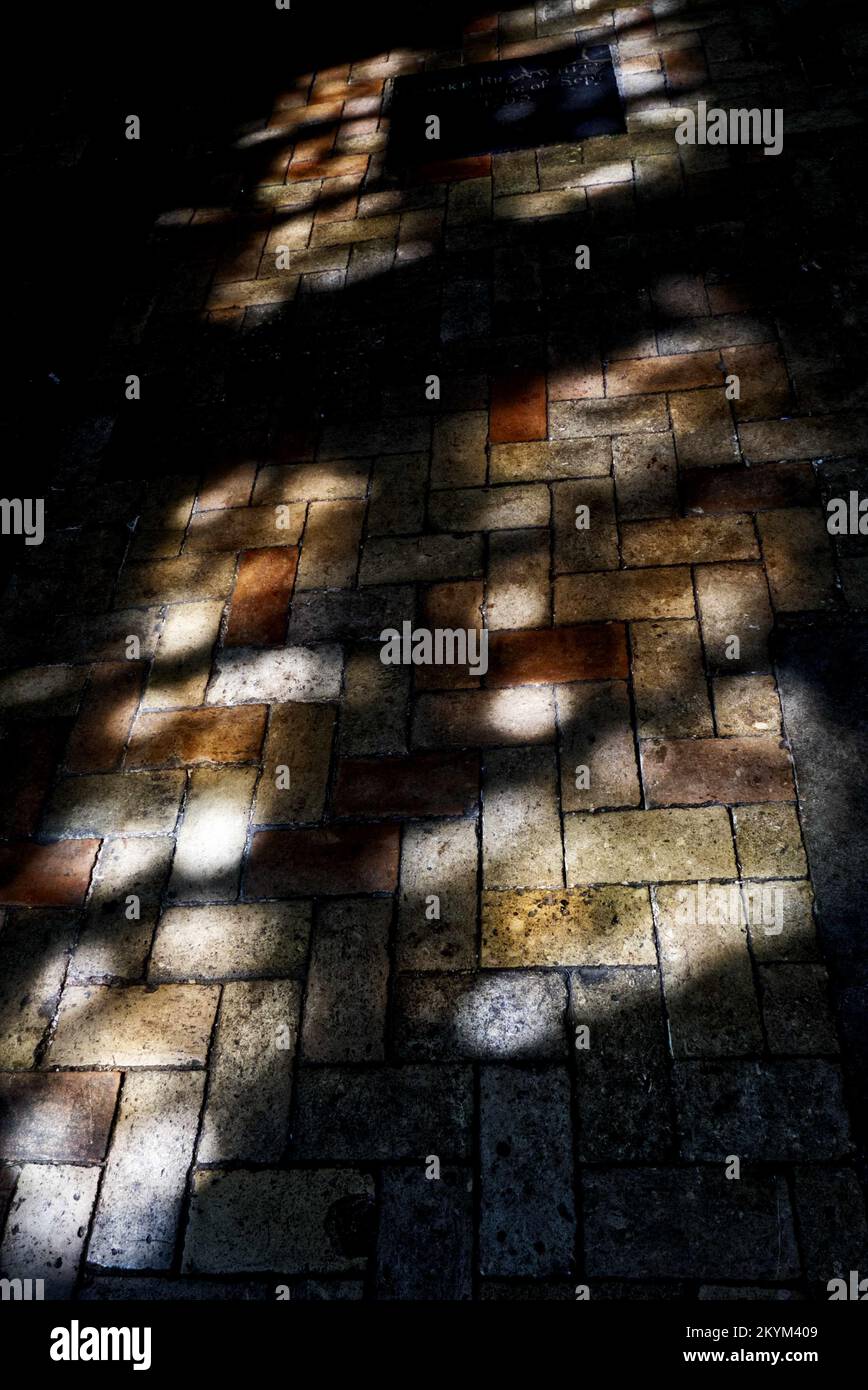 Lichtmuster aus Buntglasfenstern auf dem gepflasterten Boden einer Kirche Stockfoto