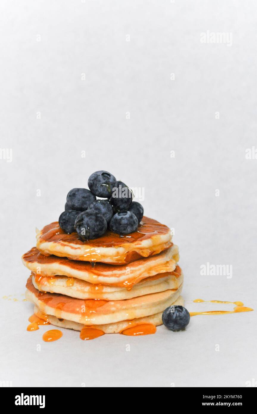 Ein Stapel Pfannkuchen, isoliert auf weißem Hintergrund mit frischen Blaubeeren und Sirup Stockfoto