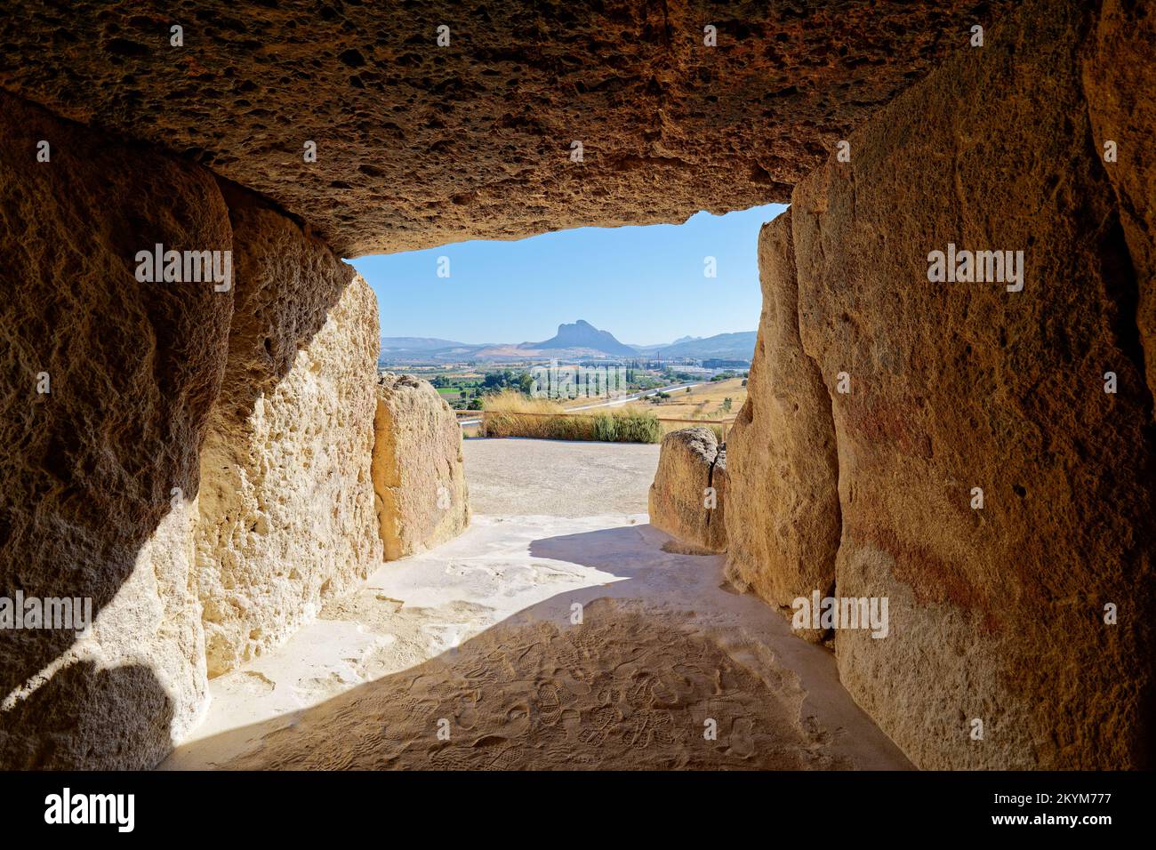 Das Innere des megalithischen Monuments Dolmens in Antequera mit dem Naturdenkmal Lovers Rock im Hintergrund. Touristenreisen nach Spanien. Stockfoto