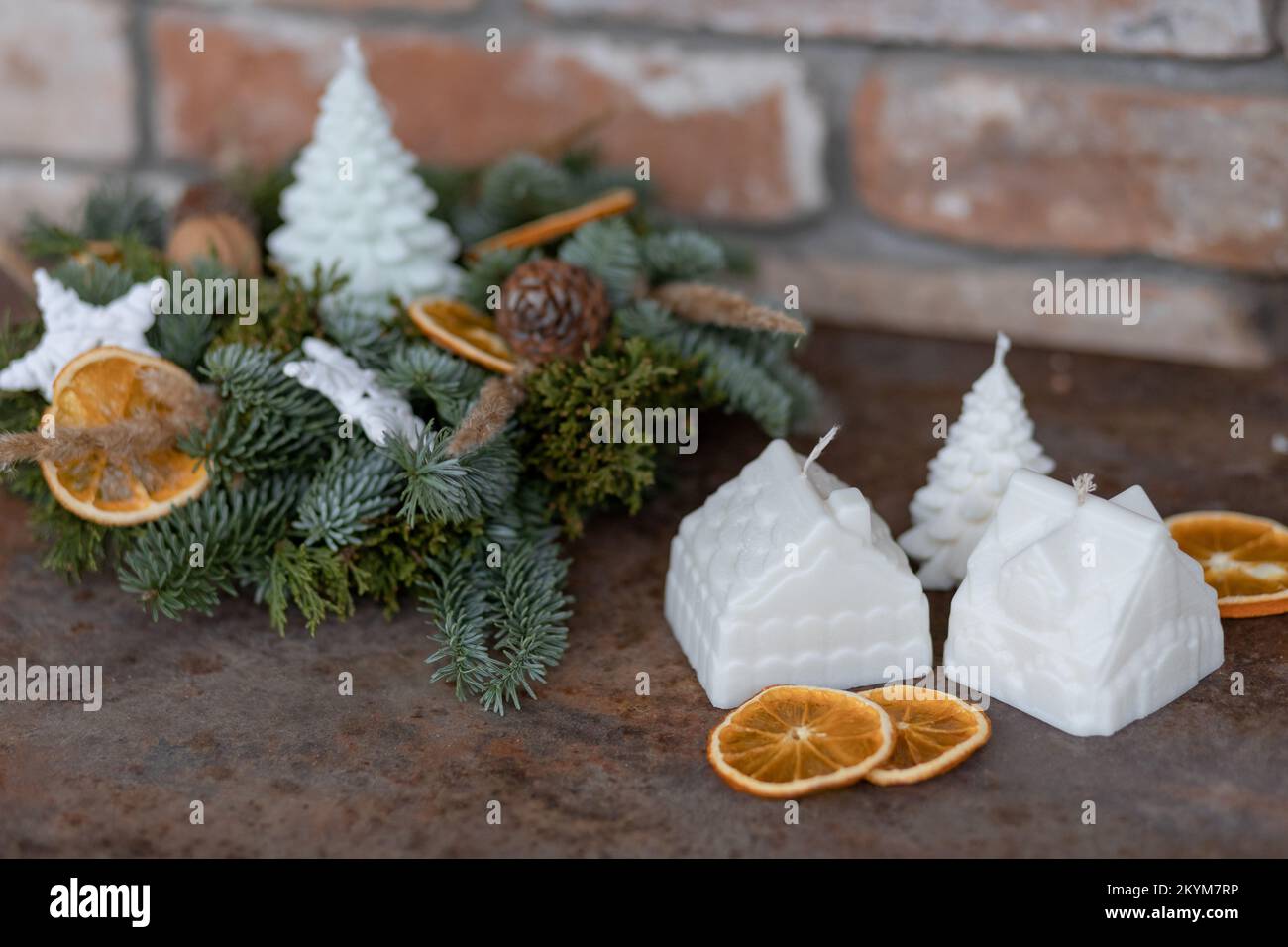 Wintertischanordnung von dekorativen Kerzen, getrockneten Orangen, Weihnachtsbaumzweigen und Zapfen auf einem rostigen Tisch Stockfoto