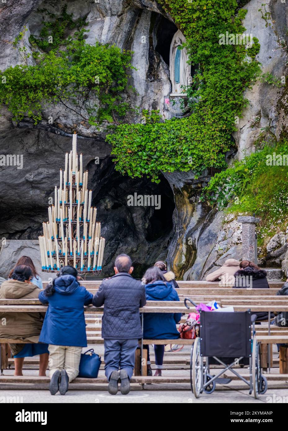 Pilger beten vor der Grotte von Lourdes mit der Statue von Bernadette Soubirous im Hintergrund (Frankreich) Stockfoto