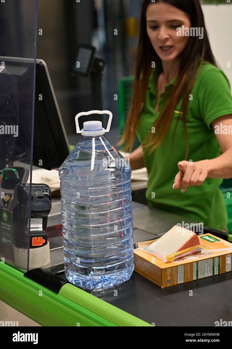 Beim Check-out im Supermarkt gab es eine große Flasche Wasser und das Essen wurde vom Personal für die Kasse auf dem Förderband berechnet Stockfoto