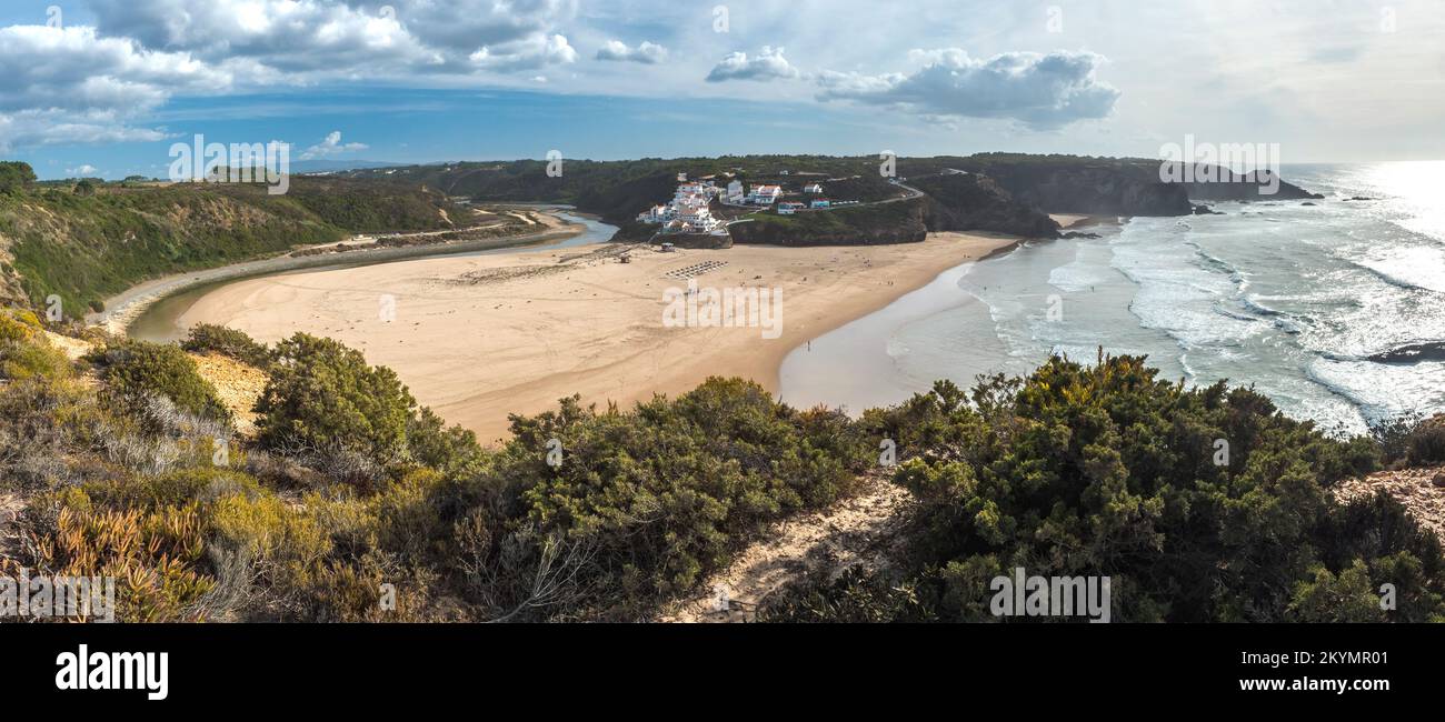 Panoramablick auf Praia de Odeceixe Mar Surfer Strand mit goldenem Sand, atlantikwellen, Flussbiegung und weißen Häusern des Dorfes Odeceixe. Rota Stockfoto