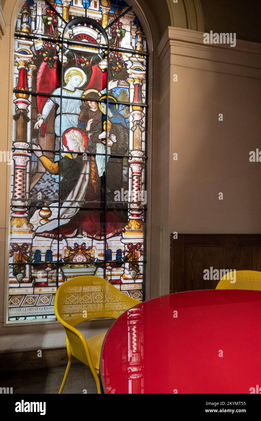 Buntglasfenster lassen das Licht in ein Café im Mercato Mayfair in der entsezierten, restaurierten St. Mark's Kirche in Mayfair, London, fließen. Stockfoto