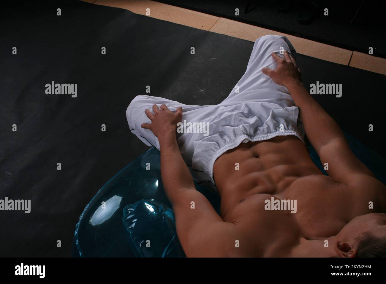 Ein Sixpack männliches Fitnesssportmodell und Fitnesstrainer, gebräuntes Modell in Boxershorts mit muskulösen bauchmuskeln. Gut ausgebildeter Fitness-Mann. Stockfoto