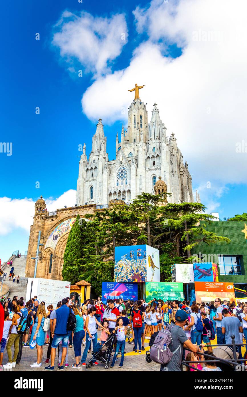 Menschenmassen im Vergnügungspark Tibidabo mit dem Tempel des Heiligen Herzens von Jesus im Hintergrund, Barcelona, Spanien Stockfoto