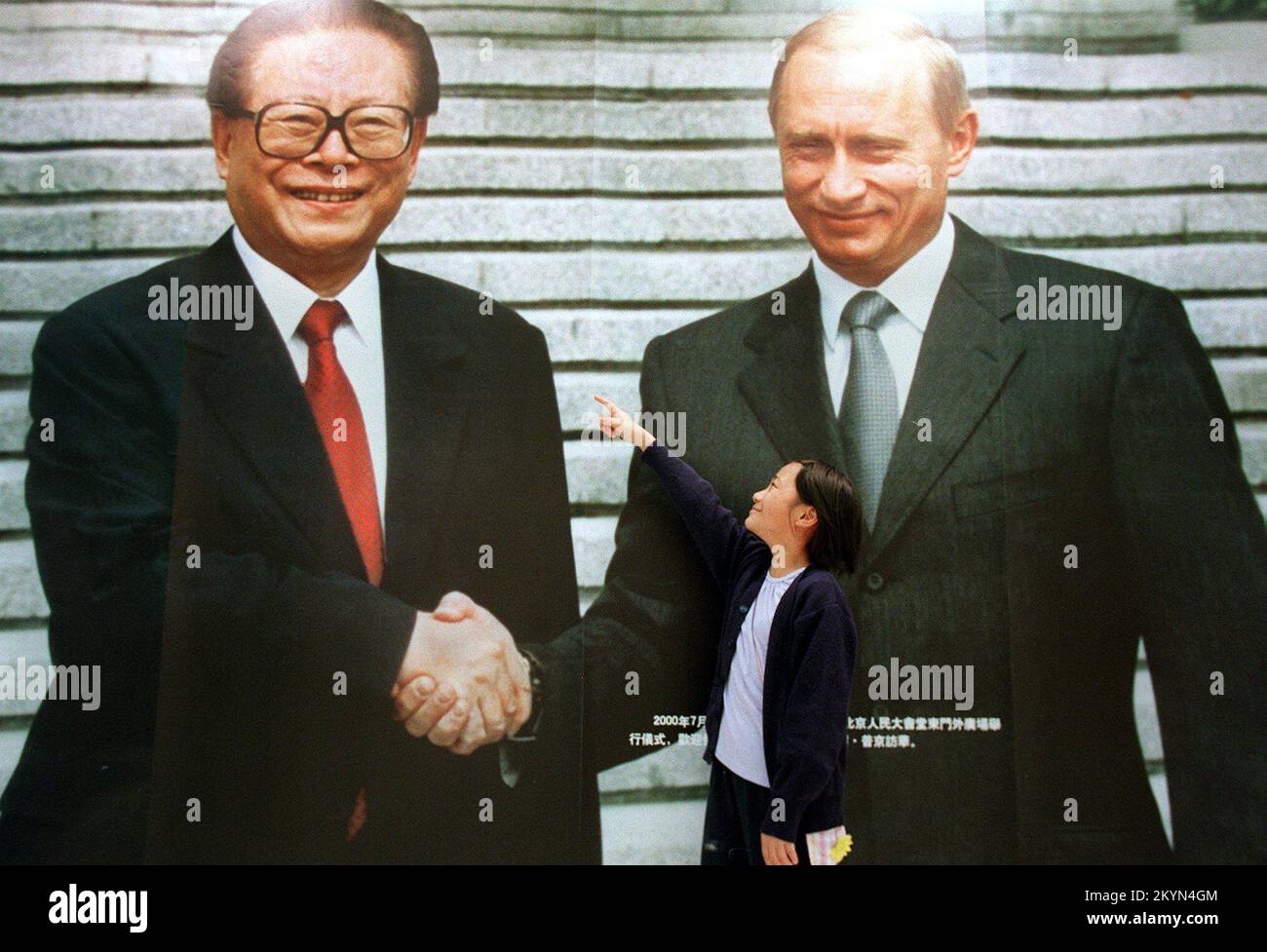 Das neunjährige Mädchen Lili Mok zeigt auf ein riesiges Foto des chinesischen Präsidenten Jiang Zemin, das während seines Chinabesuchs im Jahr 2000 die Hand schüttelte mit dem russischen Präsidenten Wladimir Putin. Die Teil einer Ausstellung wertvoller staatlicher Geschenke ist, die der Volksrepublik China von anderen Ländern überreicht werden. Die Ausstellung beginnt vom 27.. März bis zum 5.. April 2002 im Hong Kong Convention and Exhibition Centre. ***NICHT FÜR WERBEZWECKE*** Stockfoto