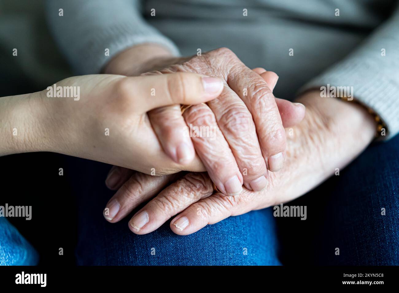 Junge Hand, die alte Hände einer Frau hält. Weichzeichner. Das Konzept der Unterstützung im Alter Stockfoto