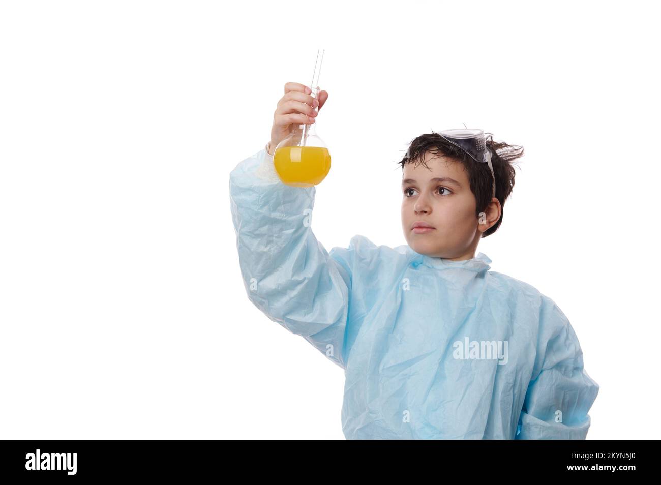 Hübscher weißer Schuljunge, Chemiker in einem weißen Laborkittel, der Laborflaschen aus Glas mit Chemikalien hält Stockfoto