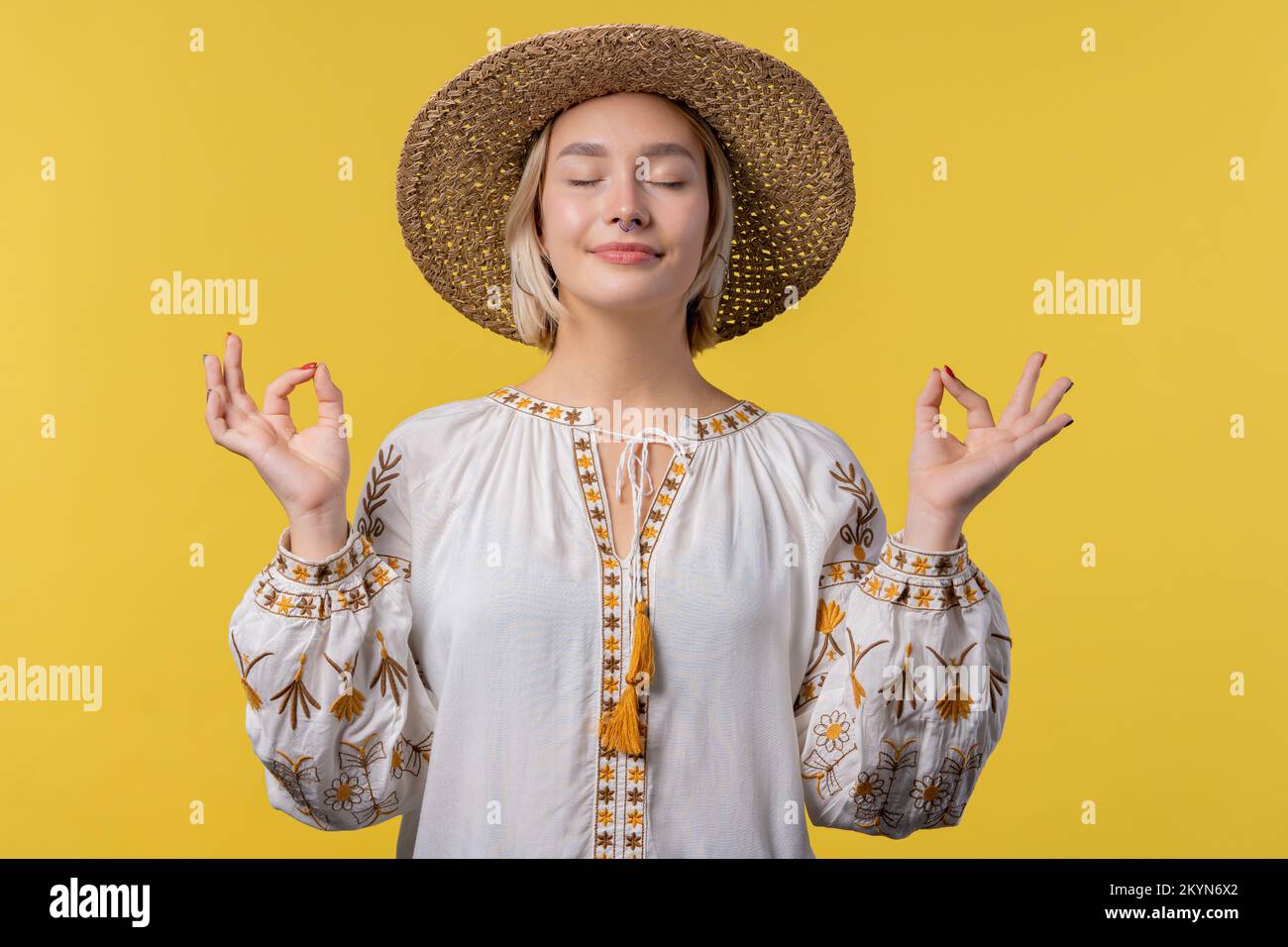 Eine ruhige ukrainerin, die sich entspannt, meditiert, Stress ablehnt. Sonniges Mädchen atmet tief, beruhigt den gelben Studiohintergrund. Yoga, moralisches Gleichgewicht, Zen Stockfoto