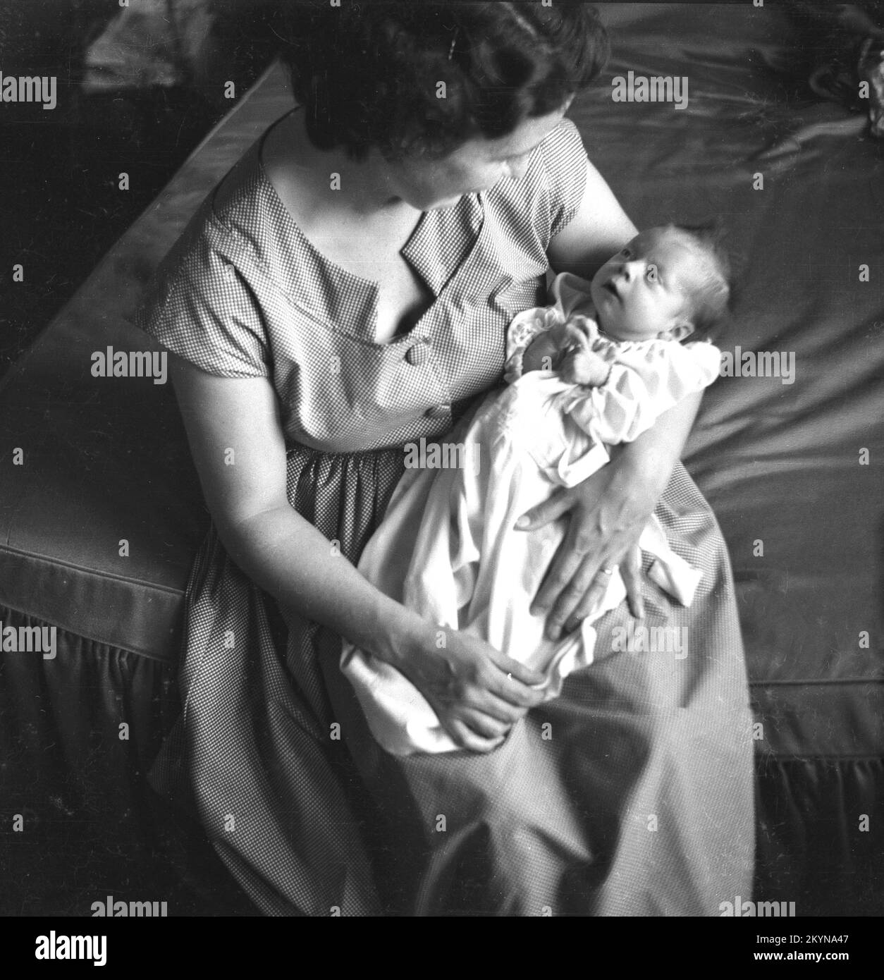 1950er, historisch, eine Dame, die am Ende eines Bettes sitzt, ihr neues Baby auf dem Schoß hält und liebevoll in ihre Augen schaut, England, Großbritannien. Stockfoto