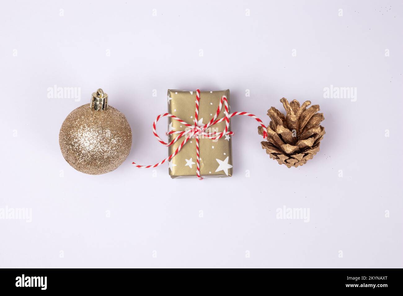 Die wichtigsten traditionellen weihnachtsgegenstände in goldenem farbraum, Ball, Geschenkbox und goldenem Kiefernzapfen auf weißem Hintergrund, Draufsicht mit Kopierbereich. Stockfoto
