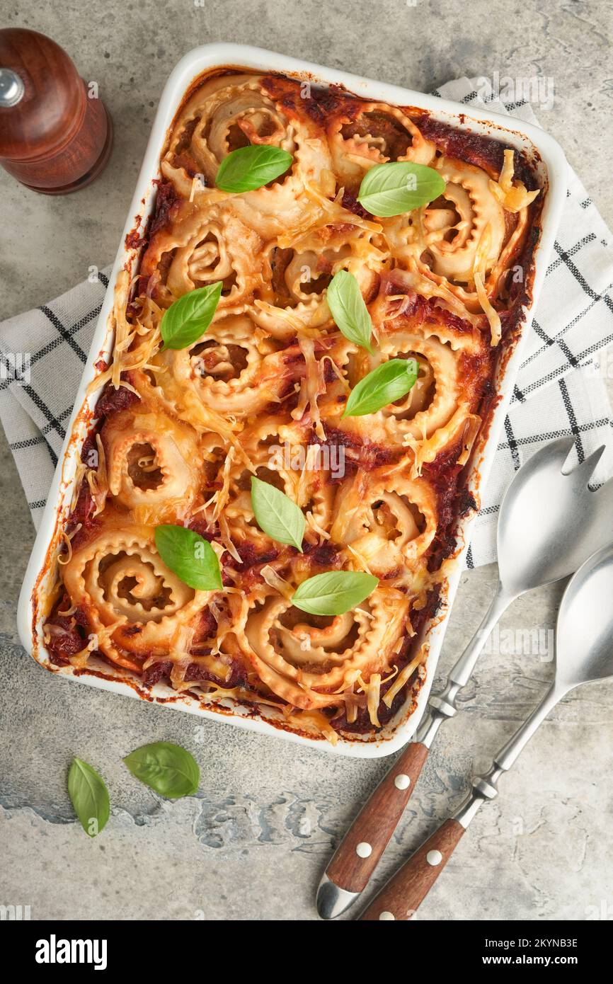 Lasagne. Hausgemachte Lasagne Pasta Rotolo mit Tomatensauce, Frischkäse und Basilikum auf weißer Pfanne auf hellem Schiefer, Stein oder Beton. ICH Stockfoto