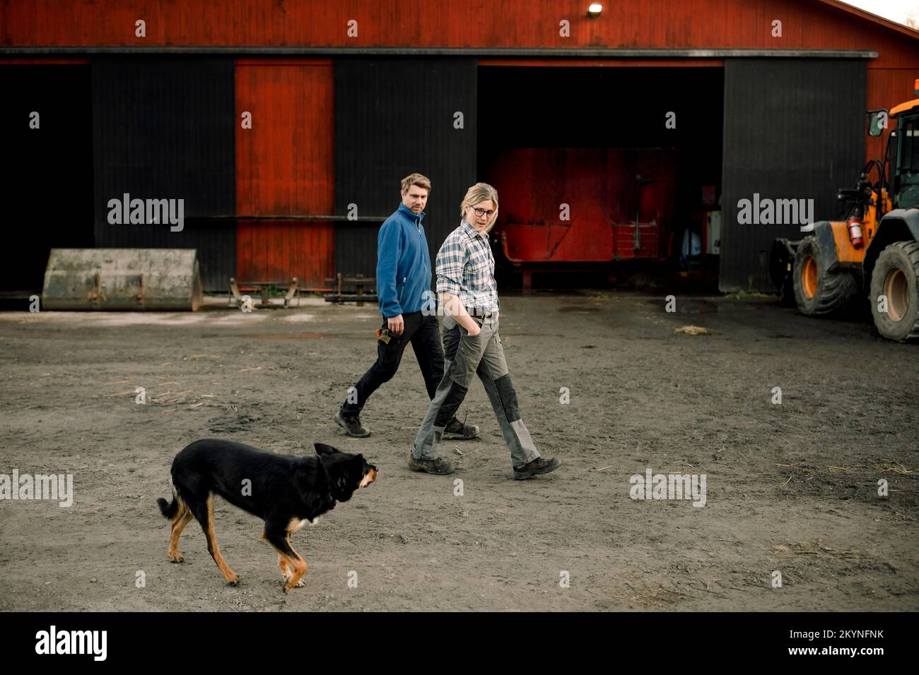 Bauern mit Hund, die zusammen vor der Fabrik spazieren gehen Stockfoto