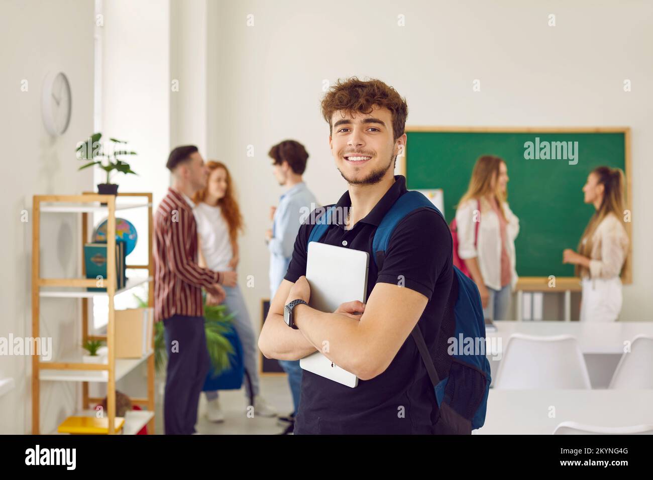 Porträt eines Schülers mit Rucksack und Tablet-Computer vor dem Hintergrund des Unterrichts mit seinen Klassenkameraden Stockfoto