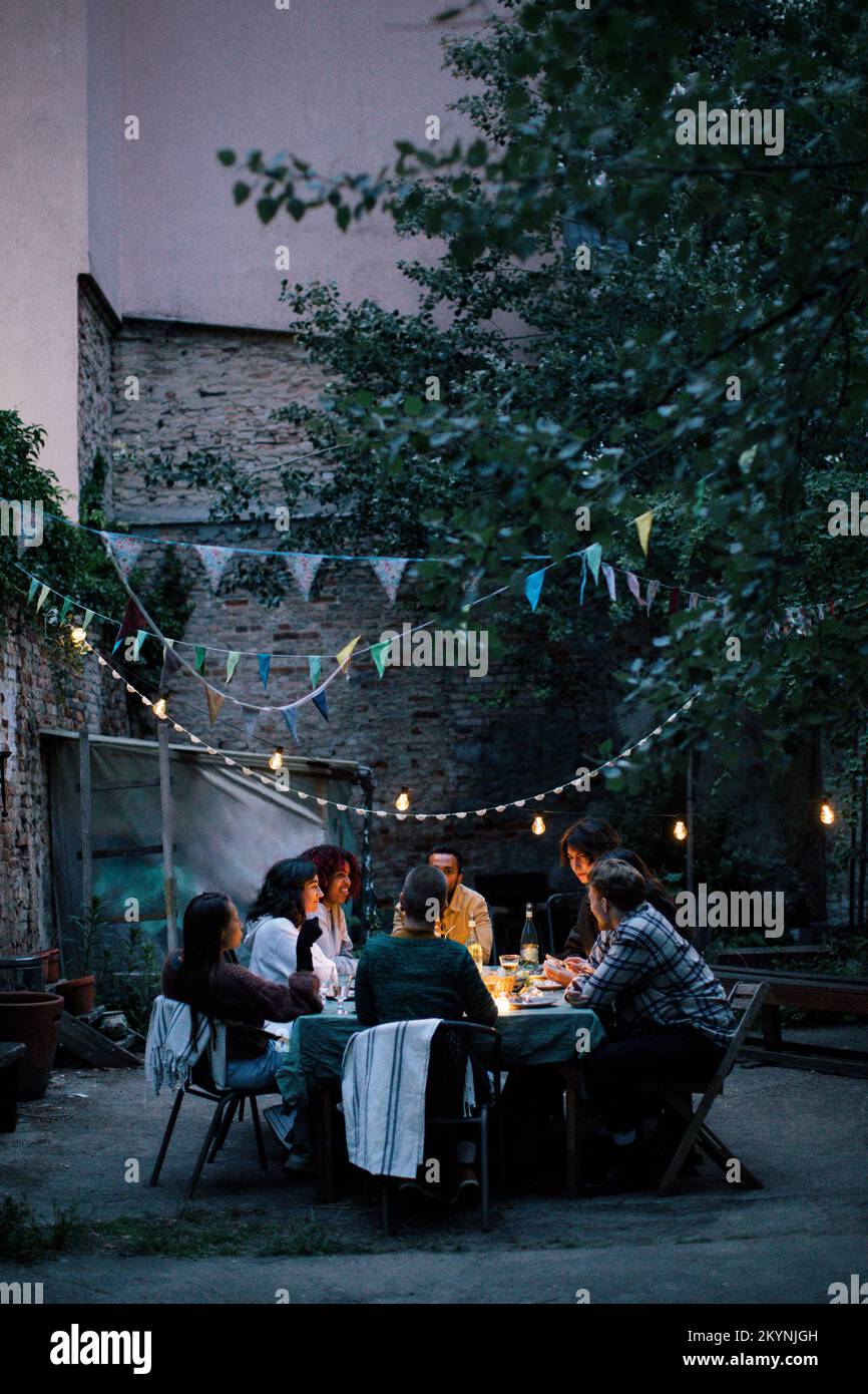 Eine Gruppe von Freunden genießt während der Dinnerparty im dekorierten Hinterhof Stockfoto