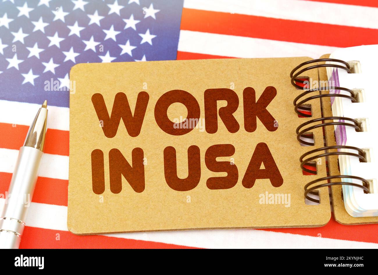 Nationales Wirtschaftskonzept. Auf der US-Flagge befindet sich ein Notizbuch mit der Aufschrift "Arbeiten Sie in den USA" Stockfoto