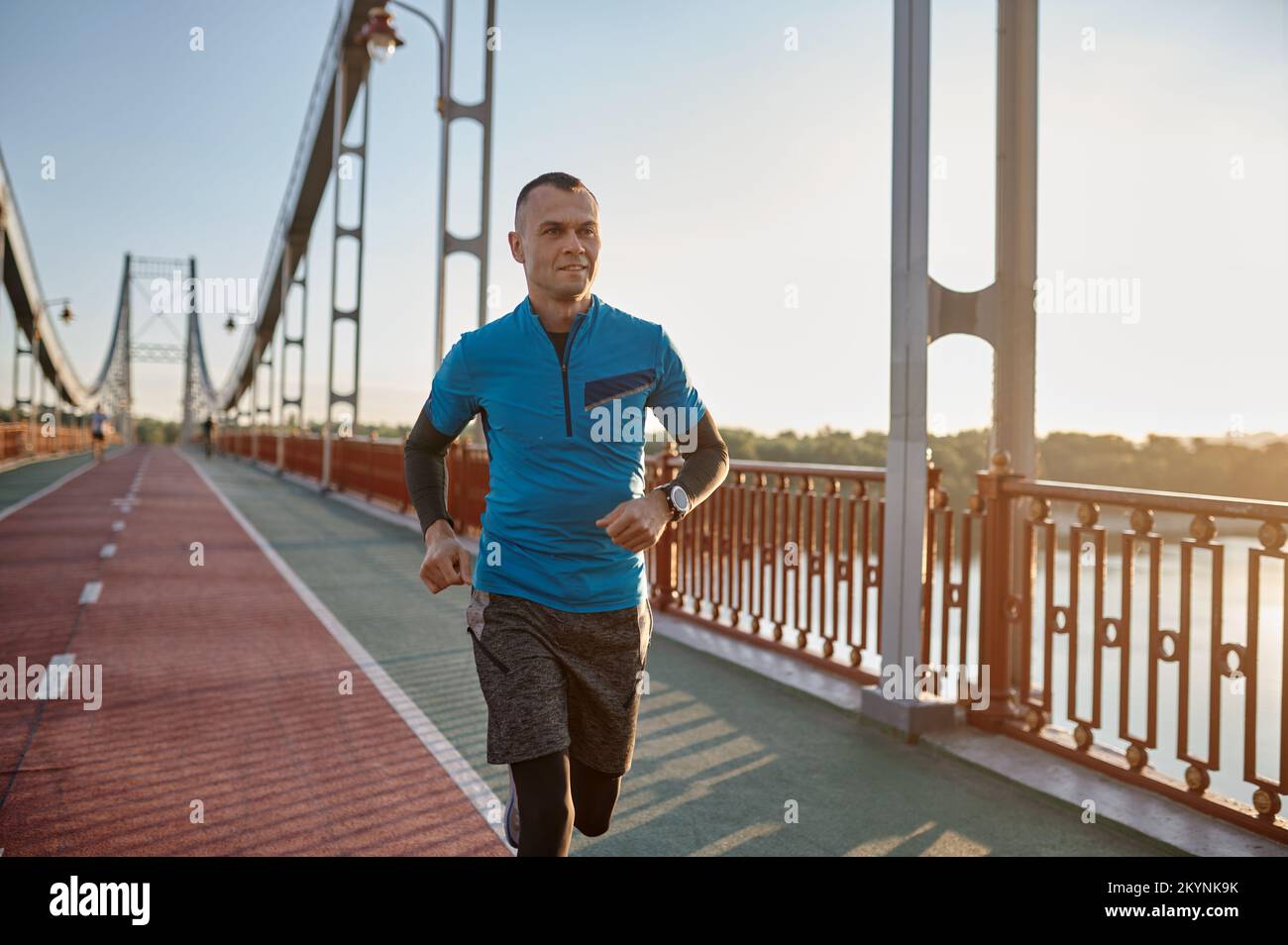 Attraktiver, fit Mann läuft schnell entlang der großen modernen Brücke Stockfoto