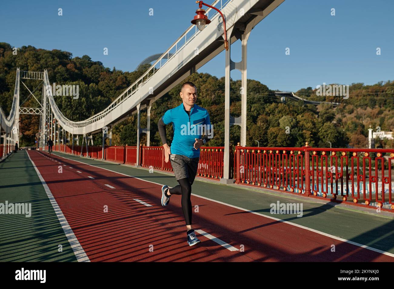 Attraktiver, passender Mann, der schnell auf der Brücke läuft Stockfoto