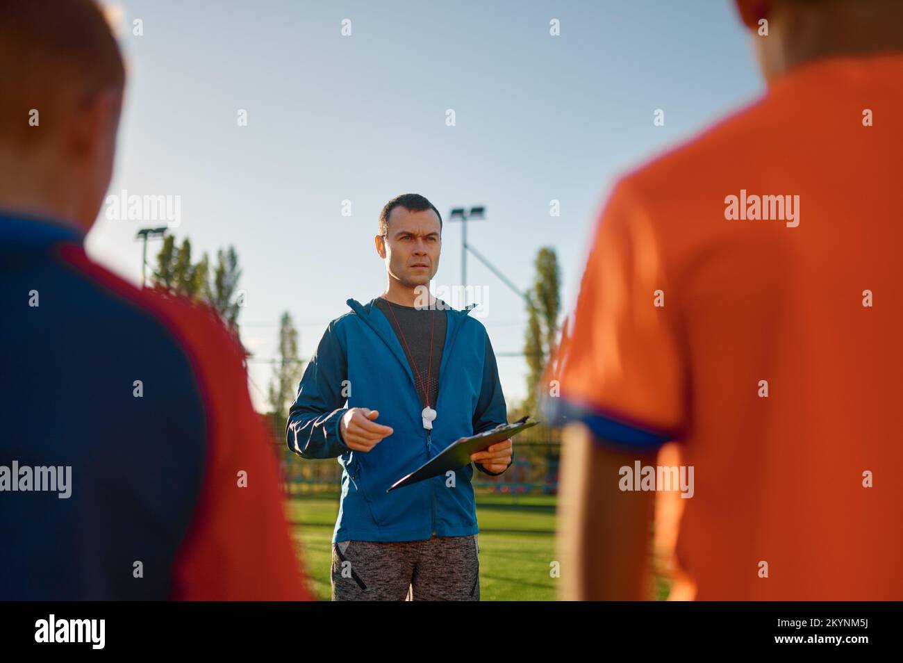 Junger Fußballtrainer, der Kindern auf dem Fußballfeld beibringt Stockfoto