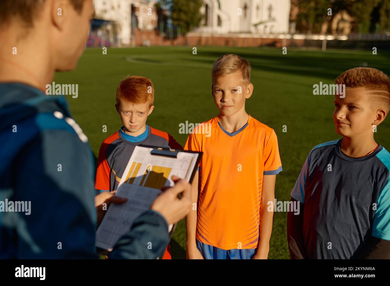 Der Fußballtrainer spricht während der Pause mit einem Team kleiner Spieler auf dem Spielfeld Stockfoto