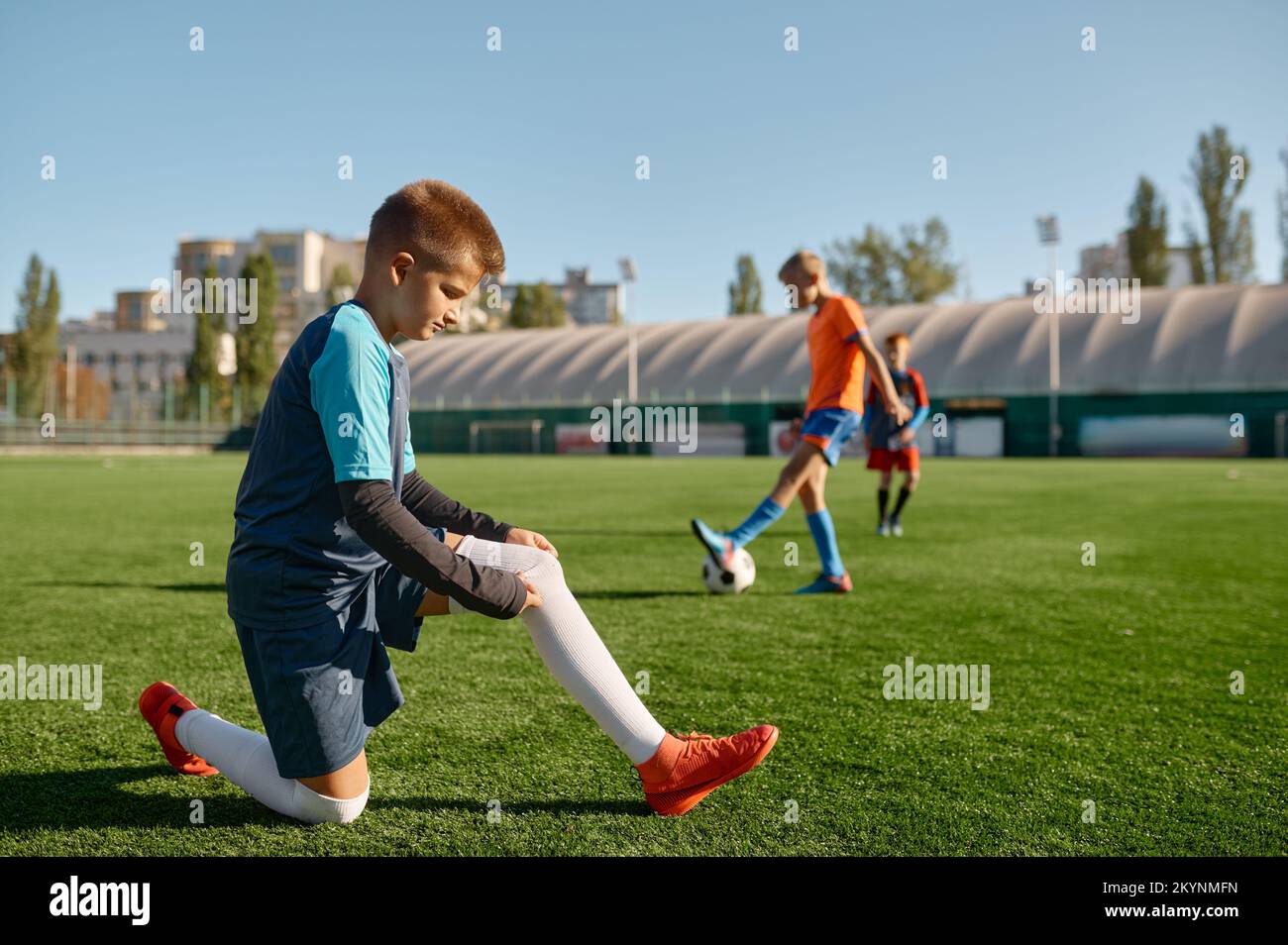 Aktive Kinder spielen Fußball auf einem grünen Sportplatz im Freien Stockfoto