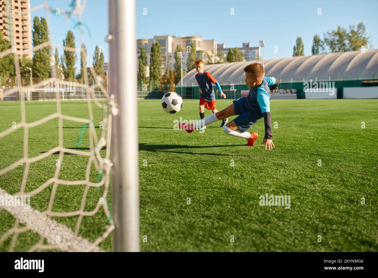 Ein Footballspieler, der den Ball auf dem Sportplatz ins Tor tritt Stockfoto