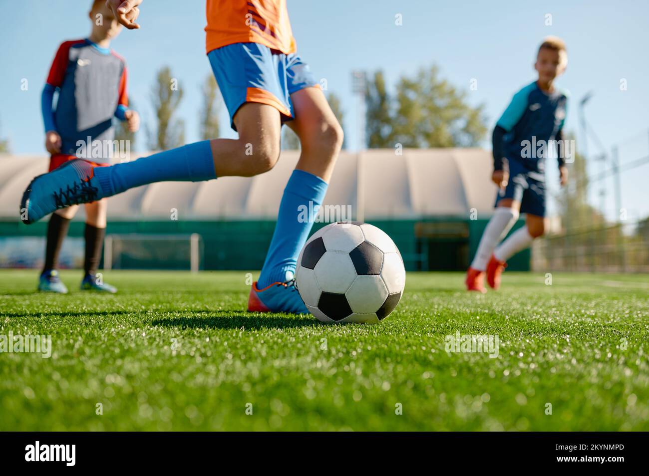 Nahaufnahme-Junge tritt Ball, während er mit Teamkollegen Fußball spielt Stockfoto