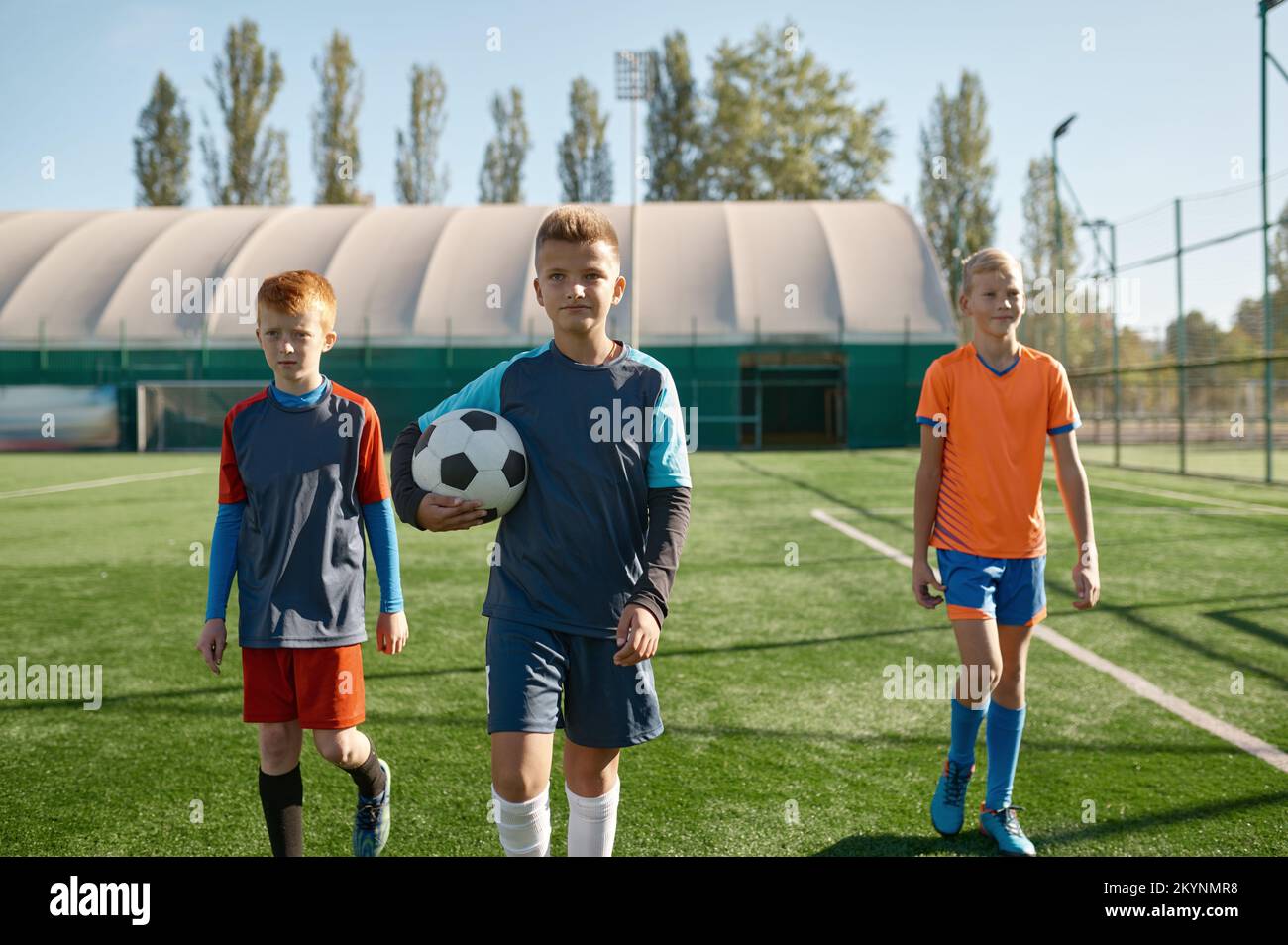 Porträt eines seriösen jungen Fußballspielers, der mit Teamkollegen auf dem Spielfeld steht Stockfoto