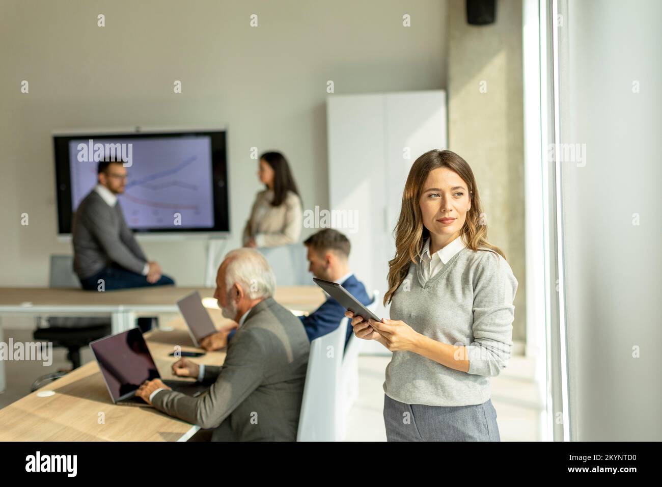 Hübsche junge geschäftsfrau beim Start Büro mit digitalen Tablet vor Ihrer Kollegen als Team Leader Stockfoto