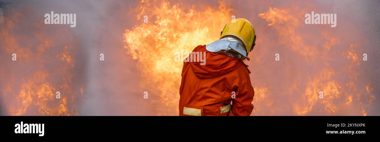 Feuerwehrmann-Rettungstraining um das Verbrennen von Flammen zu stoppen, trägt Feuerwehrmann Schutzhelm und Schutzkleidung zum Schutz vor Verbrennungen unter Verwendung von Schläuchen mit chemischem Wasser für Stockfoto