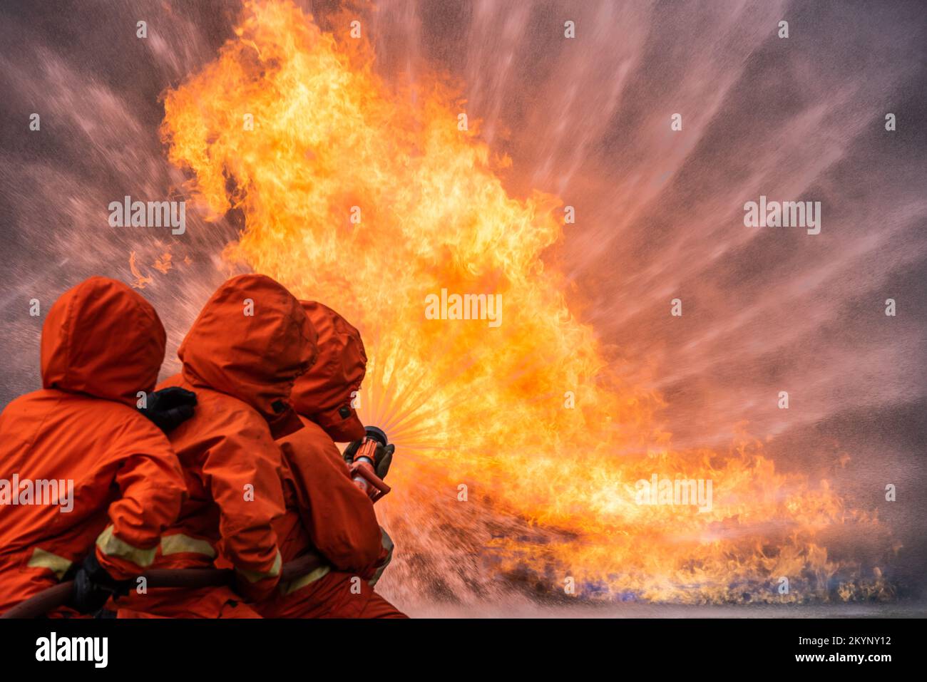 Feuerwehrmann-Rettungstraining um das Verbrennen von Flammen zu stoppen, trägt Feuerwehrmann Schutzhelm und Schutzkleidung zum Schutz vor Verbrennungen unter Verwendung von Schläuchen mit chemischem Wasser für Stockfoto