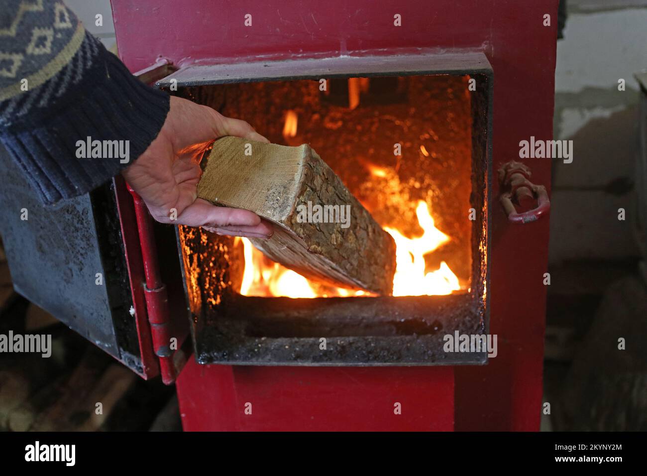 Ein Mann legt Feuerholz in den Heizofen. Stockfoto