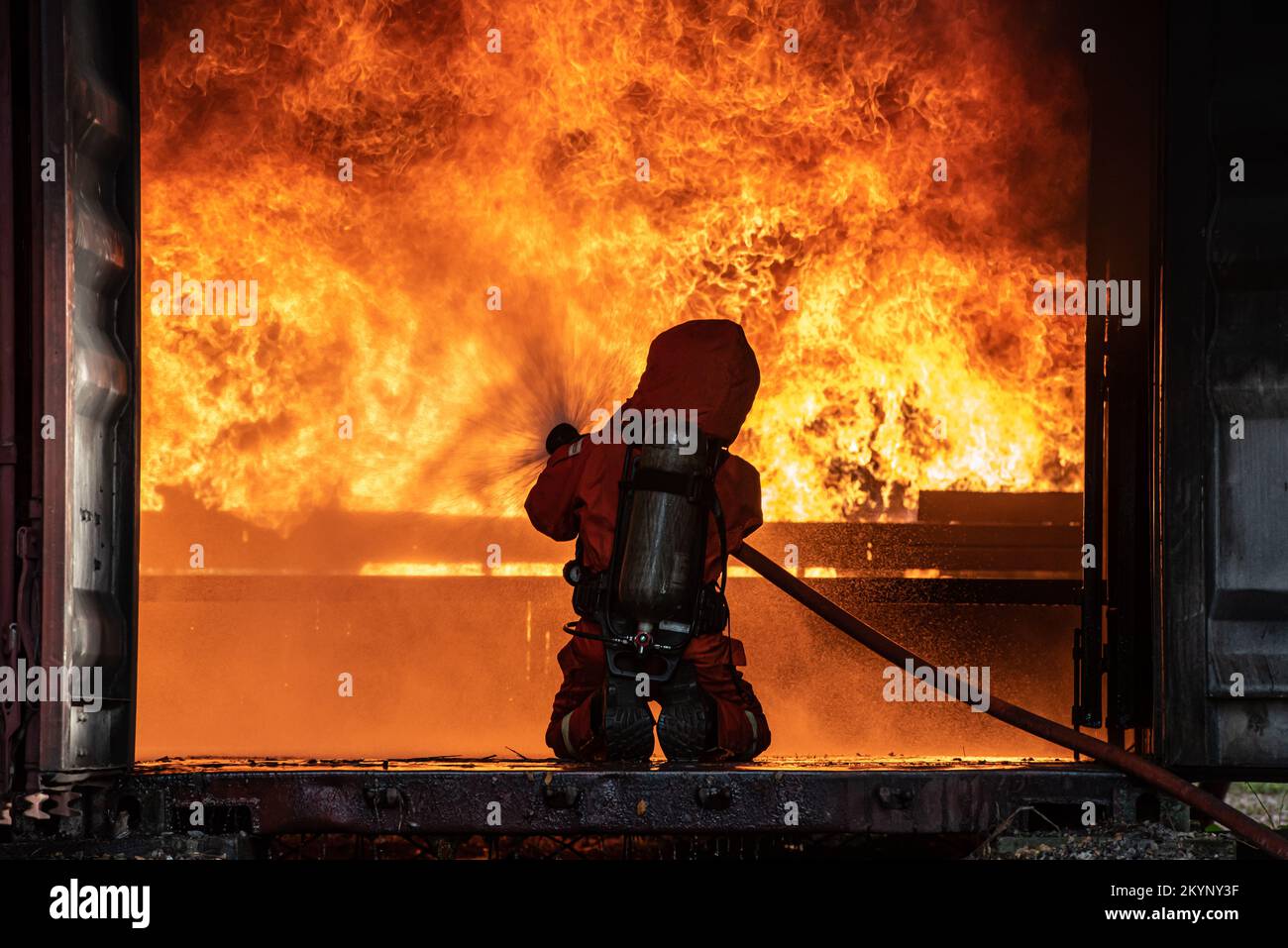 Feuerwehrmann-Rettungstraining um das Verbrennen von Flammen zu stoppen, trägt Feuerwehrmann Schutzhelm und Schutzkleidung zum Schutz vor Verbrennungen unter Verwendung von Schläuchen mit chemischem Wasser für Stockfoto