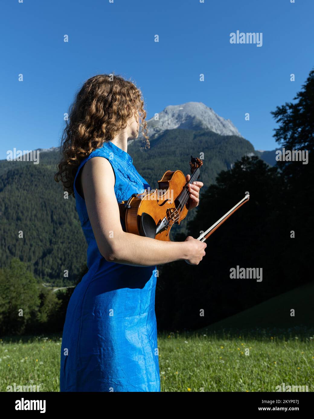 Ein junger Geiger bereitet sich darauf vor, in der Stille der Berge Geige zu spielen Stockfoto