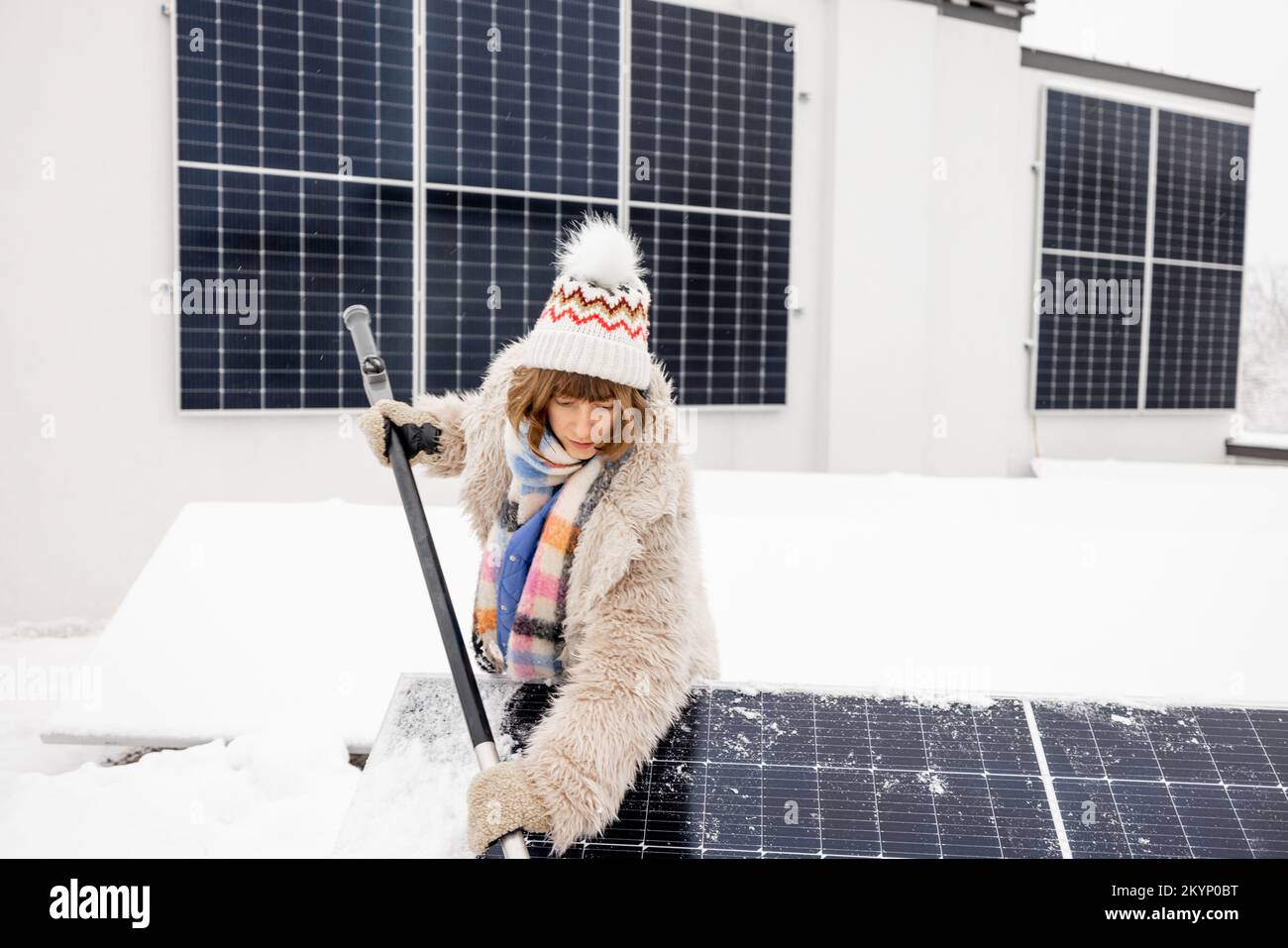 Eine Frau reinigt Sonnenkollektoren von Schnee Stockfoto
