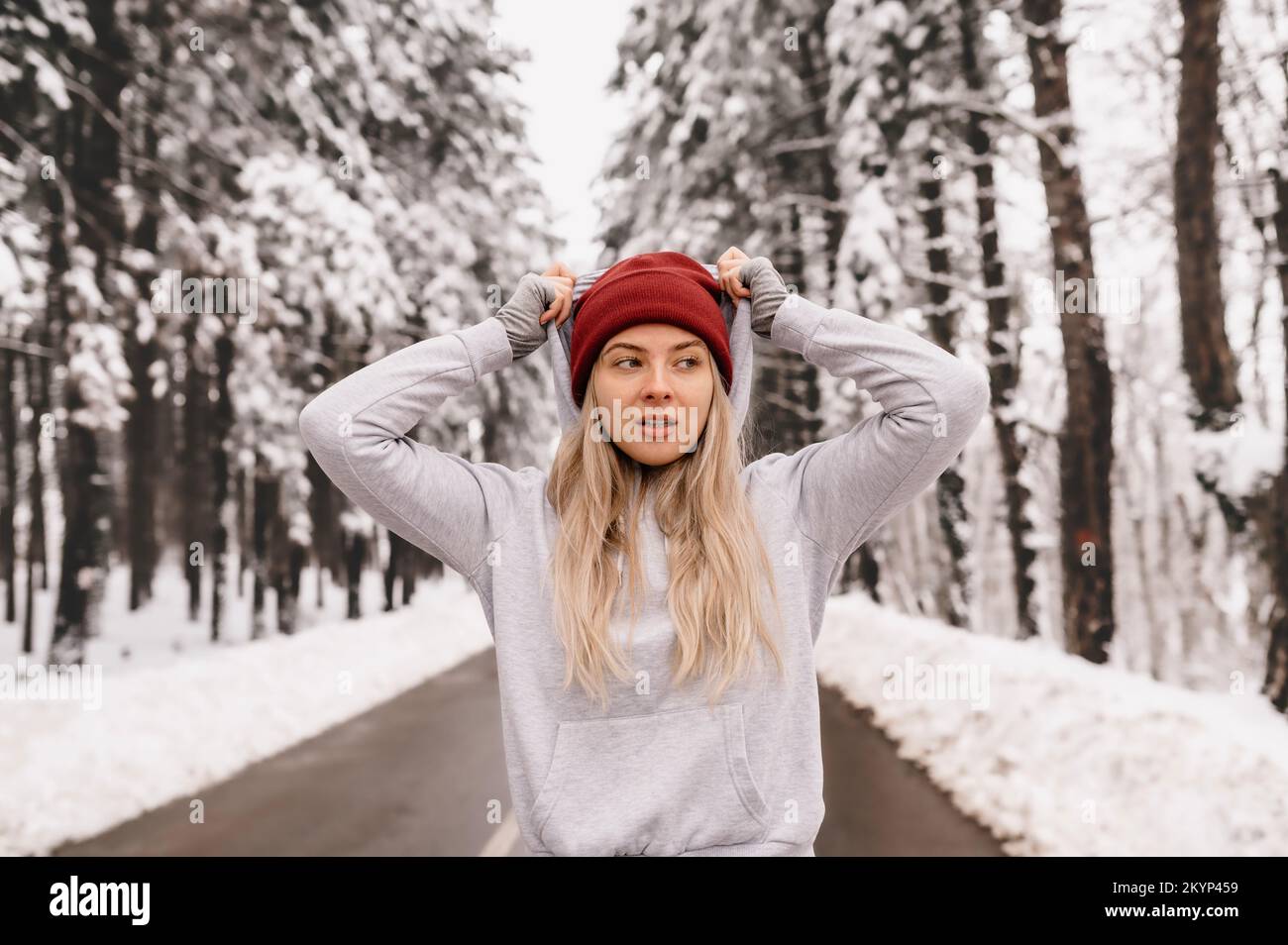 Junge athletische Frau wärmt sich vor ihrem Wintertraining an sonnigen und verschneiten Tagen auf Stockfoto
