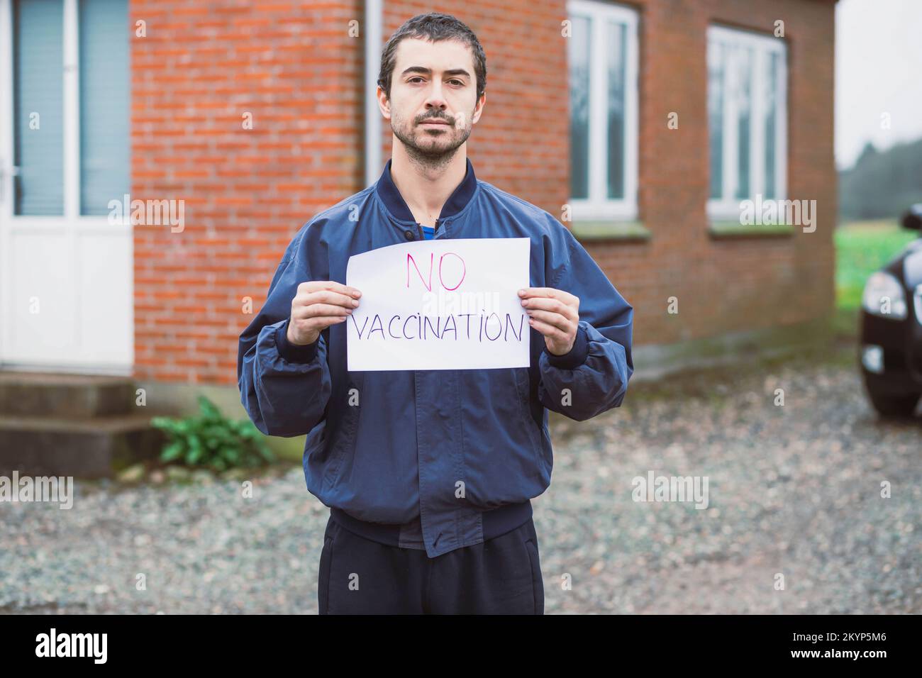 Ein Mann mit einem Anti-Impfposter in der Nähe seines Hauses Stockfoto