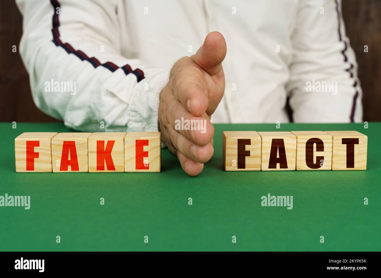 Geschäftskonzept. Ein Mann trennt die Würfel mit der Inschrift - GEFÄLSCHT oder FAKT Stockfoto