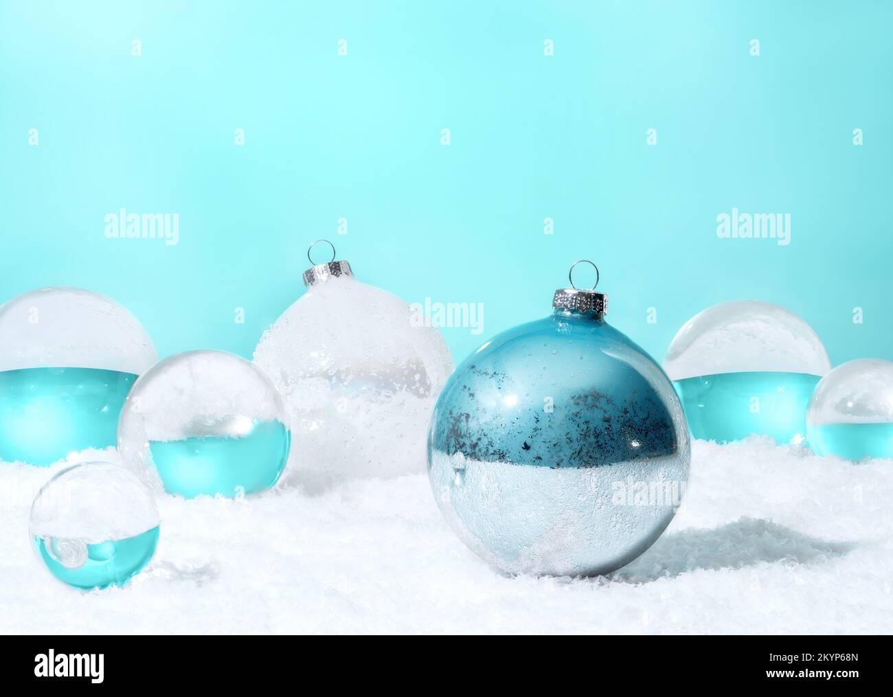 Transparente Glaskugeln und Weihnachtskugeln mit weißem Schnee auf zyanfarbenem Hintergrund. Weihnachtsdekoration Konzept. Speicherplatz kopieren. Stockfoto