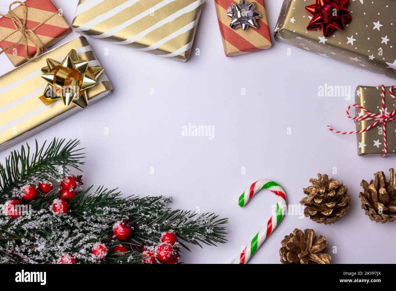 Weihnachtlicher Hintergrund mit Kopierbereich auf Weiß, Dekorationselemente mit gestreiften Geschenkboxen, Zuckerstangen, grünem Tannenbaum und Kiefernzapfen Stockfoto